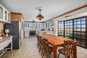 a large kitchen with a wooden table and chairs at Ocean Shores Waterfront 5 Bedroom Home Including SAUNA room in Kioloa