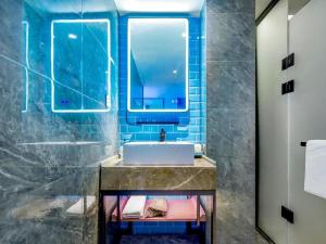 ein Bad mit einem Waschbecken und einem Spiegel in der Unterkunft Echarm Hotel Guiyang Zhongshan West Road Metro Station in Guiyang