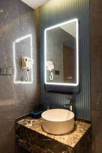 W łazience znajduje się umywalka i lustro. w obiekcie Echarm Hotel Jinzhong Yuci Wanda Plaza w mieście Jinzhong
