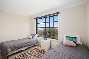 1 dormitorio con 2 camas y ventana en Ocean Shores Waterfront 5 Bedroom Home Including SAUNA room, en Kioloa