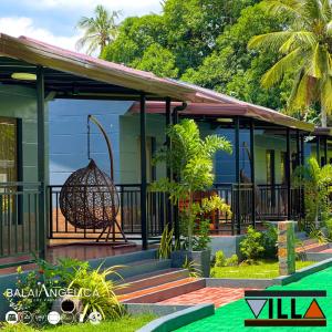 ein Haus mit einem Vogelkäfig, der von einer Veranda hängt in der Unterkunft Balai Angelica - Nature Farm & Resort in Pagsanjan