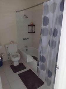 a bathroom with a tub and a toilet and a shower curtain at The Resort at West End in Negril