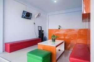 Zimmer mit roten und grünen Sitzen und einem Tisch in der Unterkunft Urbanview Syariah Wisma Nabil Solo in Lawean