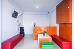 a room with red and green benches and a table at Urbanview Syariah Wisma Nabil Solo in Lawean