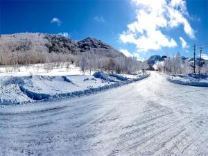 a snow covered road with a mountain in the background at Hotel & Onsen 2307 Shiga Kogen in Shiga Kogen