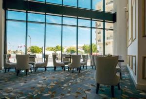 una sala de espera con sillas, mesa y ventanas en Royal sherao hotel فندق شراعوه الملكي en Doha