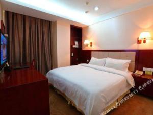 um quarto de hotel com uma cama grande e uma televisão em Bashan Hotel em Heshan