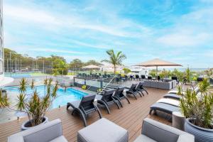 an outdoor patio with lounge chairs and a swimming pool at The Landmark 211 Resort Style holiday with pool games room and restaurant in Nelson Bay