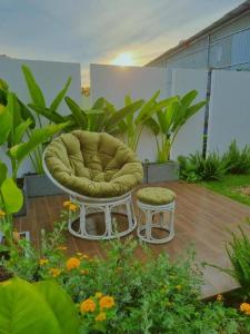 una silla y un taburete en un patio con plantas en Nha Trong Pho - The Chilling House, en Buôn Alê (1)