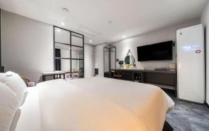 a white bedroom with a large bed and a tv at Wonju Bellino Hotel in Wonju
