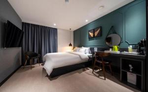 a bedroom with a bed and a desk with a mirror at Wonju Bellino Hotel in Wonju