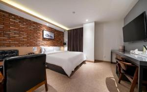 a hotel room with a bed and a brick wall at Wonju Bellino Hotel in Wonju