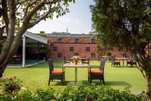 a table and chairs in a yard with a building at Dhaka Regency Hotel & Resort in Joār Sāhāra