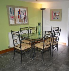 a glass table with four chairs and a glass vase at One Bedroom Character Cottage in Farthinghoe