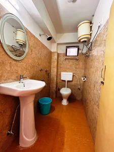 a bathroom with a sink and a toilet with a mirror at DISHA SILVER PEAK Hotel in Pelling