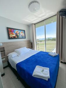 1 dormitorio con cama con sábanas azules y ventana en APARTAMENTO TURISMO PARQUE DEL CAFE -Montenegro QUINDIO, en Montenegro