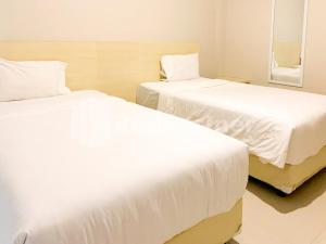 two beds in a room with white sheets at Hotel Andono RedPartner near YIA in Yogyakarta