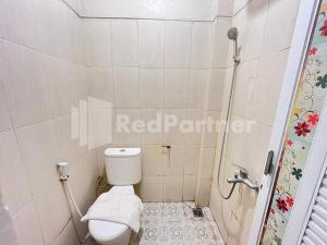a small bathroom with a toilet and a shower at Hotel Andono RedPartner near YIA in Yogyakarta