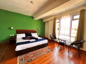 a green bedroom with a bed and a table and chairs at DISHA SILVER PEAK Hotel in Pelling