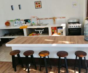 une cuisine avec un comptoir avec trois tabourets dans l'établissement Casa 3 Salinas Monterrico completamente equipada y con piscina privada, à Monterrico