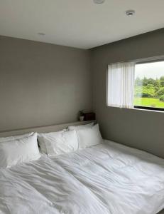 a white bed in a bedroom with a window at On Stay Jeju in Jeju