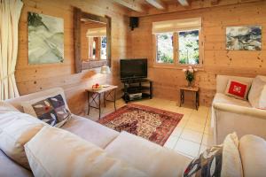 a living room with a couch and a tv at Chalet L'Ours Blanc - OVO Network in Le Grand-Bornand