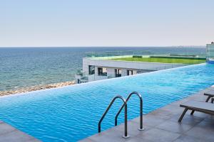 a swimming pool with the ocean in the background at RoseBay std - Infinity Pool & Spa Resort in Mamaia Nord