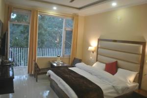 a bedroom with a large bed and a large window at Agastya Residency Dharamshala in Dharamshala