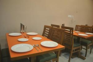 a wooden table with chairs and plates on it at Agastya Residency Dharamshala in Dharamshala