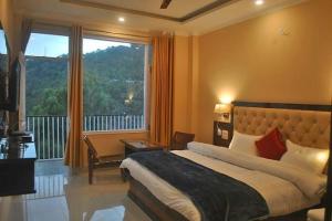 a bedroom with a bed and a large window at Agastya Residency Dharamshala in Dharamshala