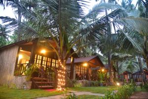a palm tree with lights in front of a house at INAS OCEAN FRONT in Canacona