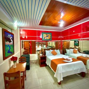 a bedroom with two beds and a table and a dining room at Hotel Ventura Isabel in Iquitos