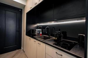 uma cozinha preta com um lavatório e um fogão em Triple A - Stylish Seven On The Pedestrian - FREE Parking! em Atenas