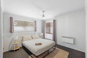 a white bedroom with a bed and a window at Lovely Living in Lovely Banks