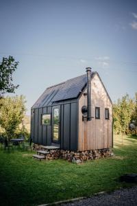 a wooden house with a black roof on a grass field at AIVA Glamping in Partizánske