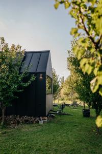 un cobertizo negro en un campo con árboles en AIVA Glamping, en Partizánske