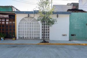 una puerta de garaje blanca con un árbol delante de ella en Casa Jazmín (Casa familiar) en Santa Cruz - Huatulco