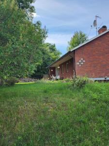 a brick house with a grassy yard in front of it at Ananis Stuga in Svartå