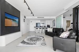 - un salon avec un canapé et une télévision murale dans l'établissement Luxury Broadbeach Apartment with Ocean Views, à Gold Coast