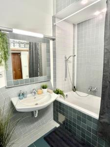 ein Badezimmer mit einem Waschbecken, einer Badewanne und einem Spiegel in der Unterkunft James Bond Apartment old town in Bratislava