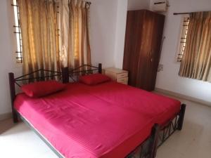 a bedroom with a large red bed with red sheets at Happy Beach House in Chennai