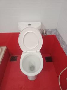 a bathroom with a white toilet in a red room at Happy Beach House in Chennai