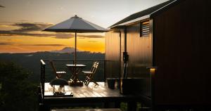 eine Terrasse mit einem Tisch, Stühlen und einem Sonnenschirm in der Unterkunft Bobocabin Dieng, Wonosobo 