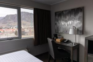 una camera d'albergo con scrivania, letto e finestra di The Thompson Hotel a Kamloops