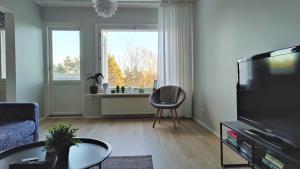 uma sala de estar com uma televisão e uma cadeira em Green Getaway - near Helsinki Vantaa Airport, top-floor, free parking & wifi em Vantaa