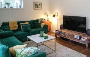 a living room with green couches and a flat screen tv at Lovely Home In Blid With Kitchen in Blidö