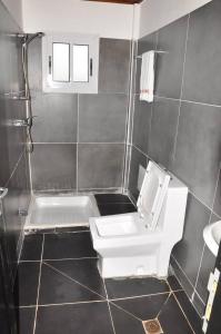 y baño con aseo blanco y lavamanos. en Explorez le charme et élégance de MMEWEL HÔTEL en Douala