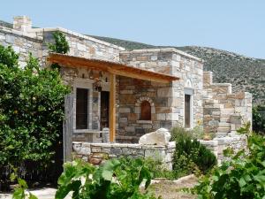 a stone house with a door in a yard at Traditional stone-built cottages Azalas in Moutsouna Naxos