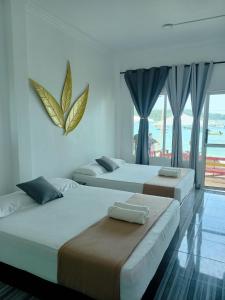 two beds in a bedroom with a view of the ocean at Perhentian Bay Chalet in Perhentian Island