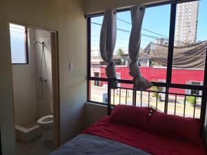 Hotel San Felipe Iquique في إكيكي: غرفة نوم بسرير ونافذة ودورة مياه